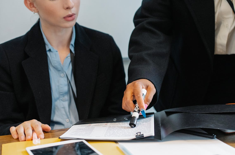 Two professionals reviewing a compliance document together at a desk.