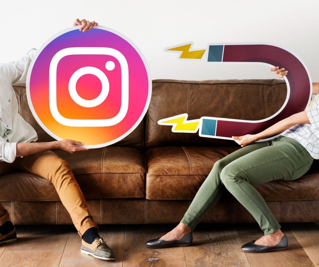 Two people on a couch holding an Instagram logo and magnet props.