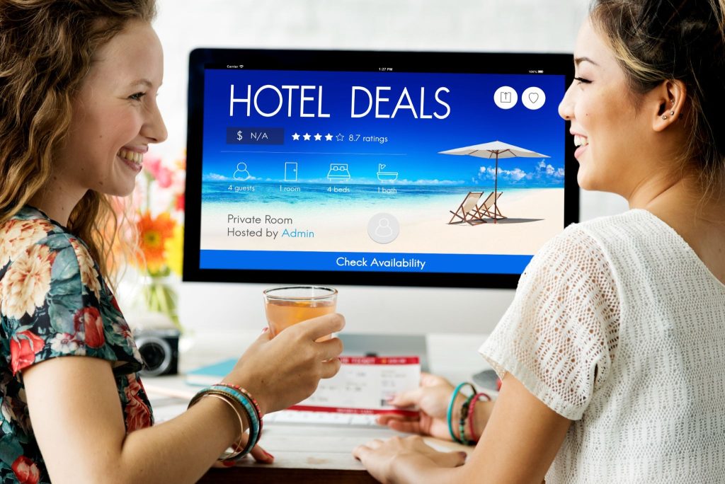 Two travelers reviewing an Airbnb booking page on a laptop after seeing a Facebook ad.