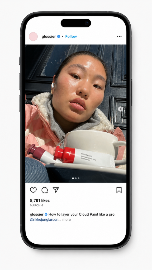 Glossier Instagram post mimicking organic UGC, a customer with dewy, sunlit skin holds a Cloud Paint blush tube, captioned "How to layer your Cloud Paint like a pro’”