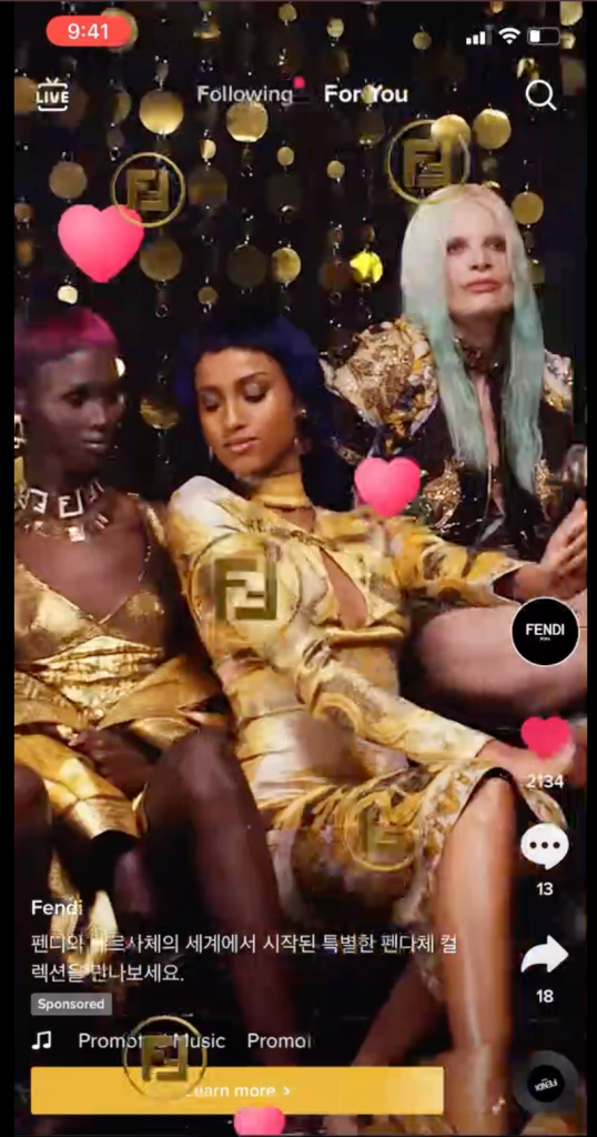 Fendi TikTok Super Like gesture ad screenshot showing three models in gold, with floating pink heart icons and Fendi "FF" logos rising up the frame, a "Sponsored" label, and a "Learn more" CTA bar, illustrating the double-tap Super Like interaction format.