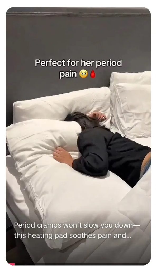 TikTok ad screenshot showing a person curled up in bed with the overlay "Perfect for her period pain," illustrating how dropshippers in wellness categories open problem-solution demos with a visible pain point.