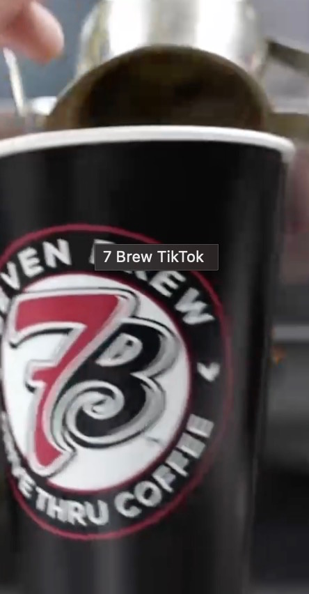 Close-up of a black 7 Brew Drive Thru Coffee cup being filled with coffee.