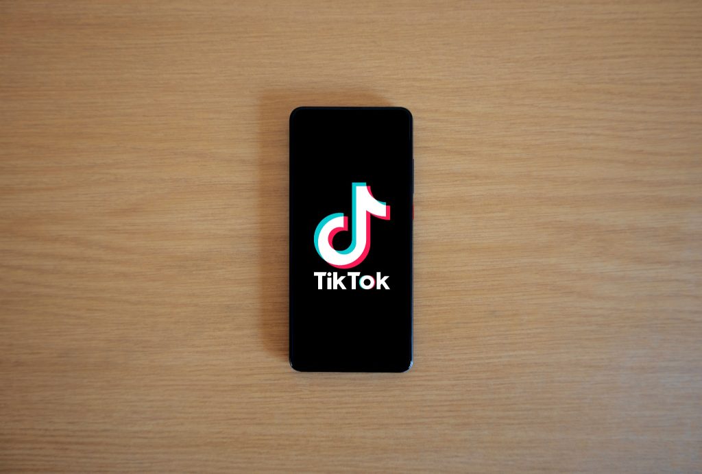 Smartphone displaying the TikTok logo and name on screen, resting on a wooden surface.