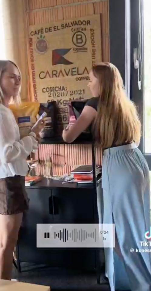 Two women conversing at a Caravela Coffee display inside Konesso's coffee shop, filmed candidly.