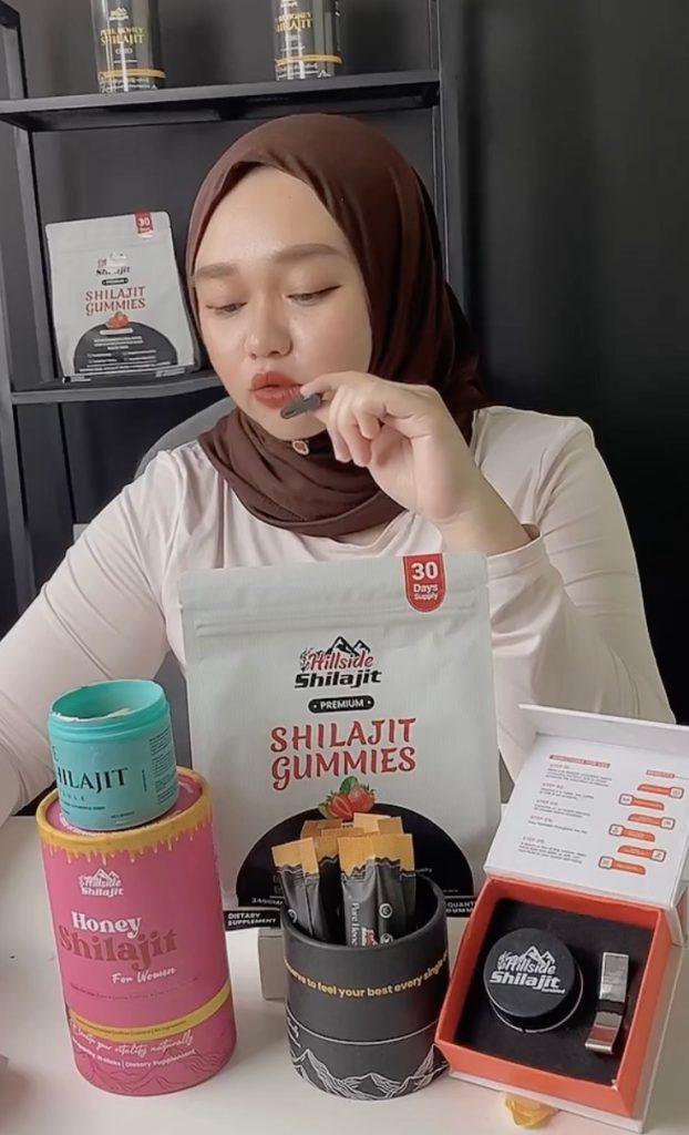 Woman speaking about Shilajit gummy beside branded supplement products.