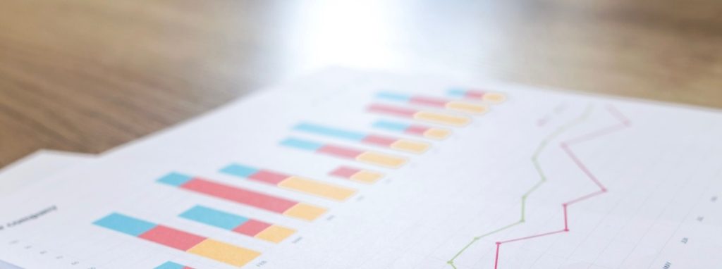Printed report with colorful bar charts and line graphs on a wooden desk surface.