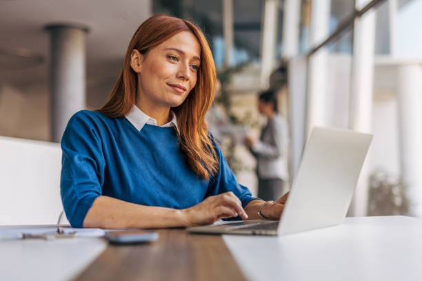 Woman at a laptop researching Facebook ad keyword strategies in a modern office setting.