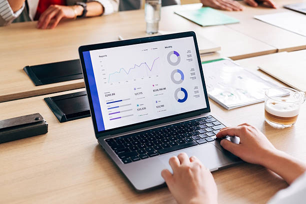 Laptop displaying marketing analytics dashboard with charts and metrics during a business meeting.