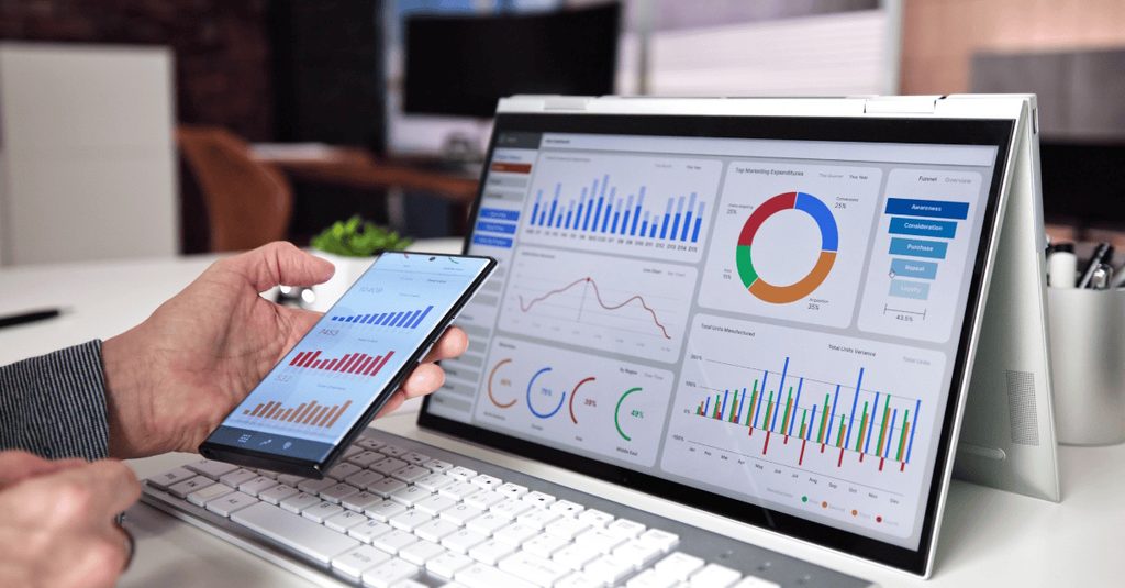 Marketing analytics dashboard on laptop and phone displaying ad performance charts and funnel metrics.