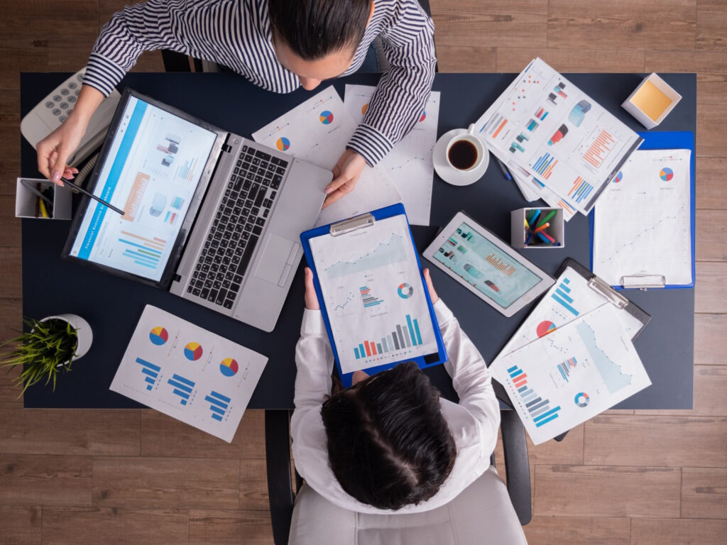 Two marketers analyzing ad performance charts and reports to diagnose and fix ineffective Facebook ad campaigns.