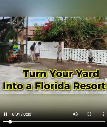 Still from a vertical walkthrough video showing a crew laying sod across a prepared front lawn.